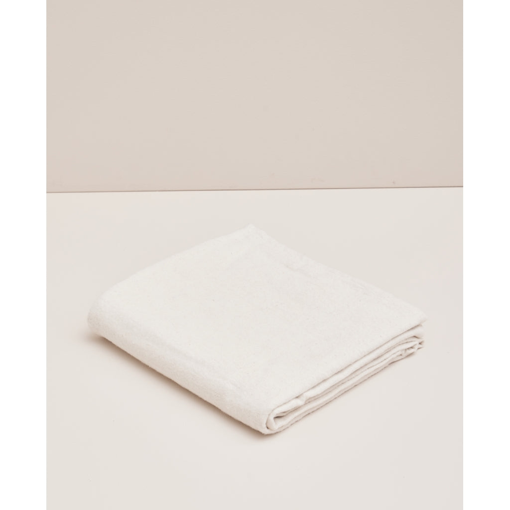 Couverture de yoga Moonchild Natural en coton biologique, pliée sur un fond beige clair.