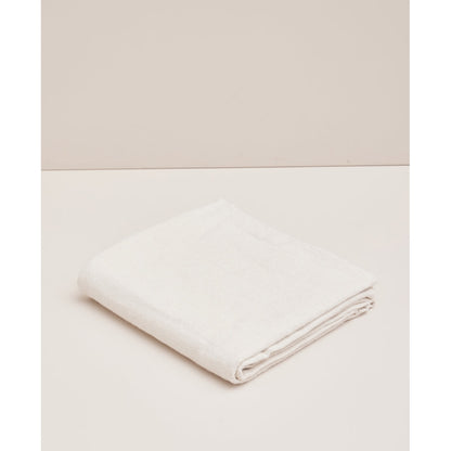 Couverture de yoga Moonchild Natural en coton biologique, pliée sur un fond beige clair.
