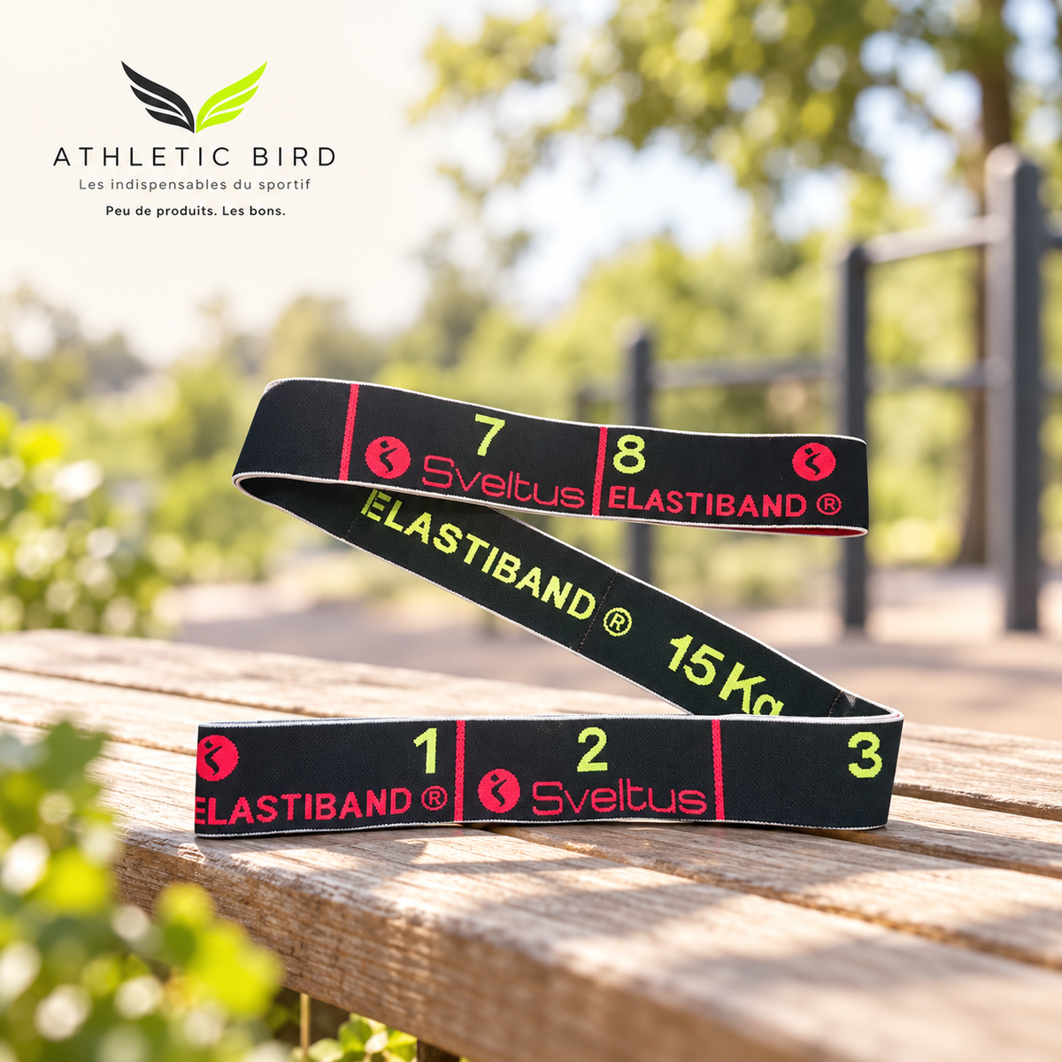 Elastiband Sveltus noir 15 kg posé sur un banc en bois dans un parc sportif, avec logo Athletic Bird