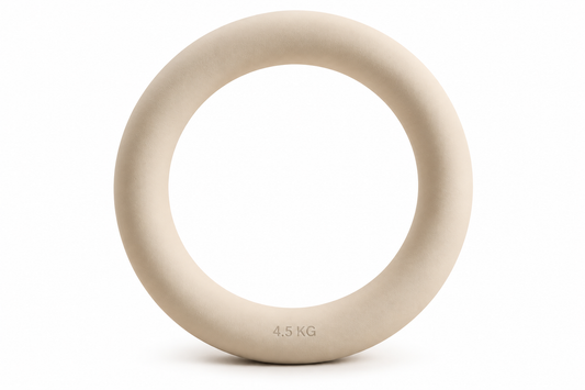 Anneau lesté Weight Ring de 4,5 kg, coloris beige crème, présenté seul de face sur fond blanc. Forme circulaire épaisse avec surface mate et légèrement texturée, ouverture centrale et inscription « 4.5 KG » sur la partie inférieure. Accessoire de fitness conçu pour les exercices de renforcement musculaire, de Pilates et de mobilité, sélectionné par Athletic Bird.