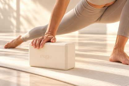 Bloc de yoga Myga crème utilisé comme support des mains lors d’une posture de yoga en fente.