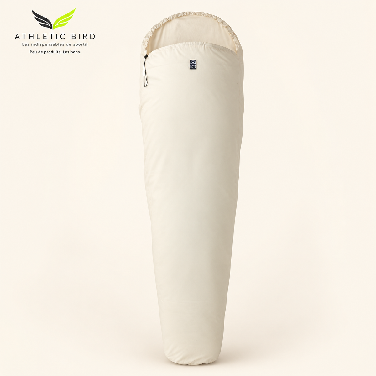 Drap de sac Wilsa Outdoor en coton écru, forme sarcophage, sur fond clair, logo Athletic Bird en haut à gauche
