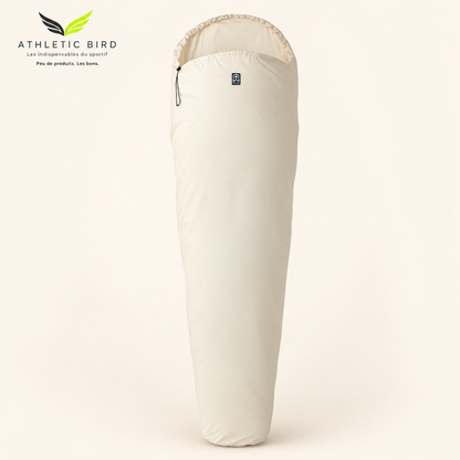 Drap de sac Wilsa Outdoor en coton écru, forme sarcophage, sur fond clair, logo Athletic Bird en haut à gauche